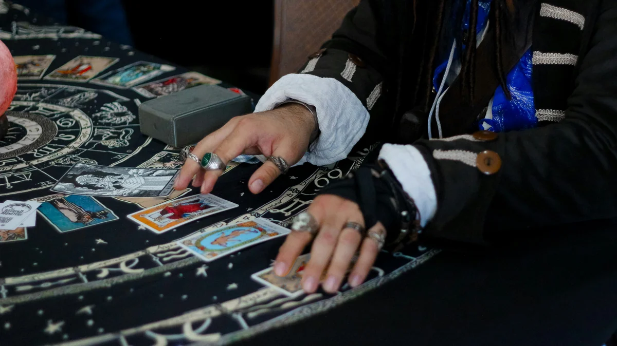 Hands arranging tarot cards on a celestial patterned cloth. - affordable psychic phone readings