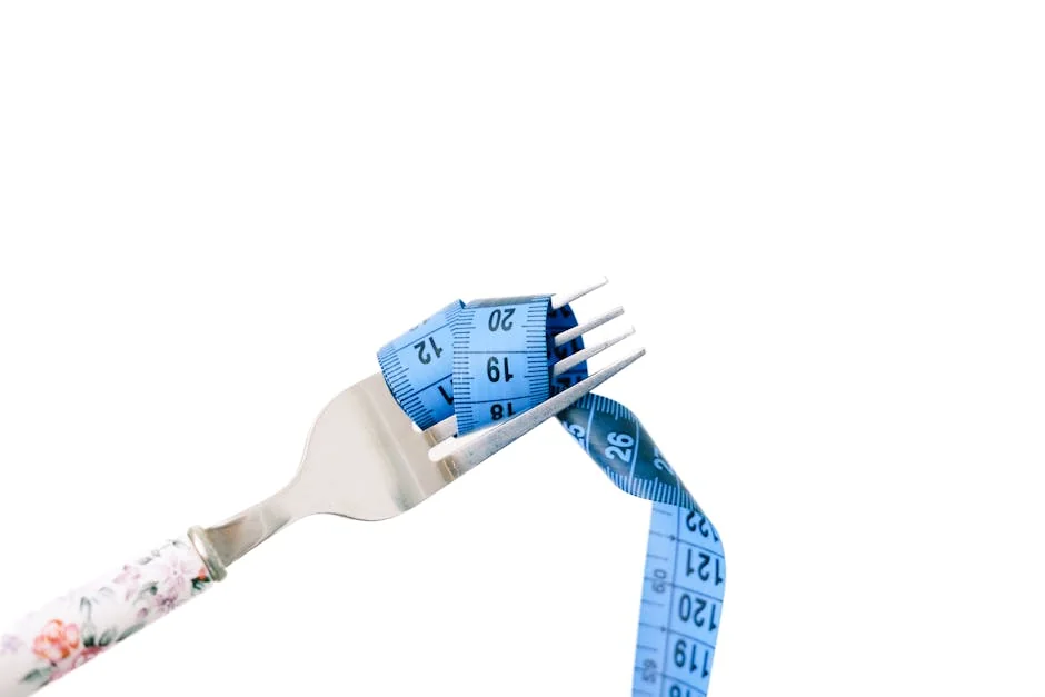 A fork entwined with a blue measuring tape, symbolizing dieting and weight management. - calorie management