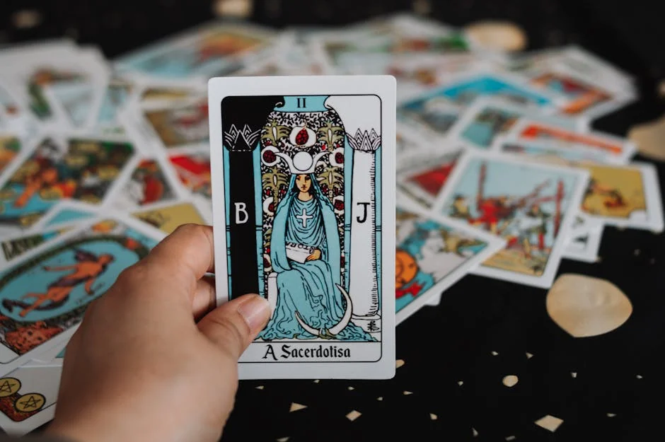 Close-up of a hand holding The High Priestess tarot card among scattered tarot cards. - keen vs california psychics