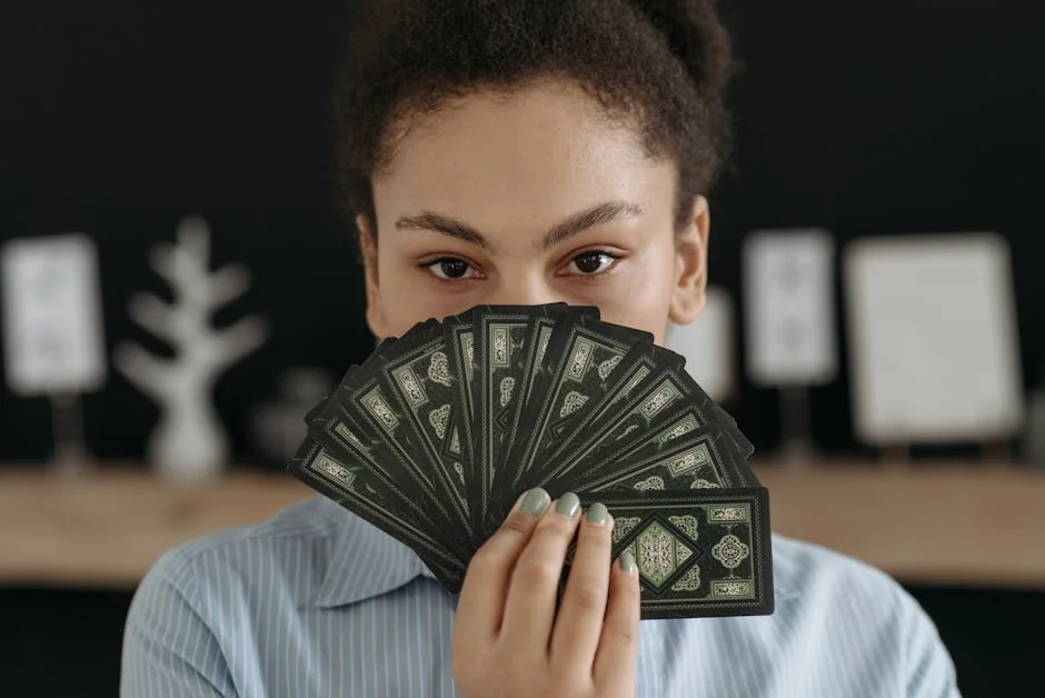 A woman with a focused expression holding a fan of tarot cards, conveying mystery and reflection. - keen psychic reviews