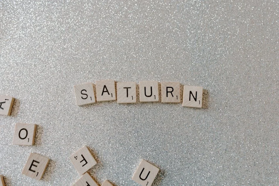 Scrabble tiles forming the word SATURN on a sparkling glitter background, space theme. - mercury retrograde survival tips