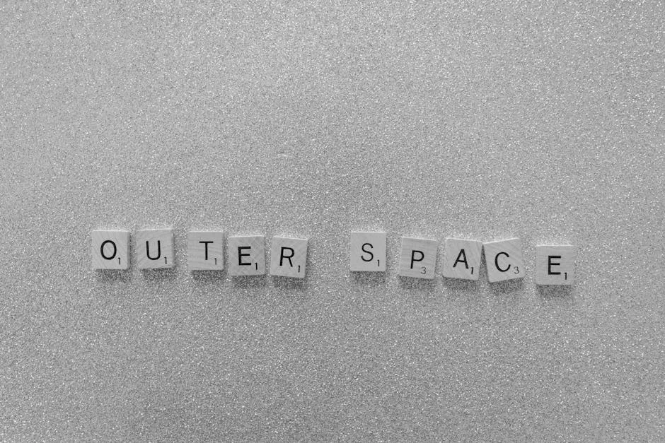 Scrabble tiles spelling 'Outer Space' on a shimmering glitter surface in black and white. - mercury retrograde survival tips