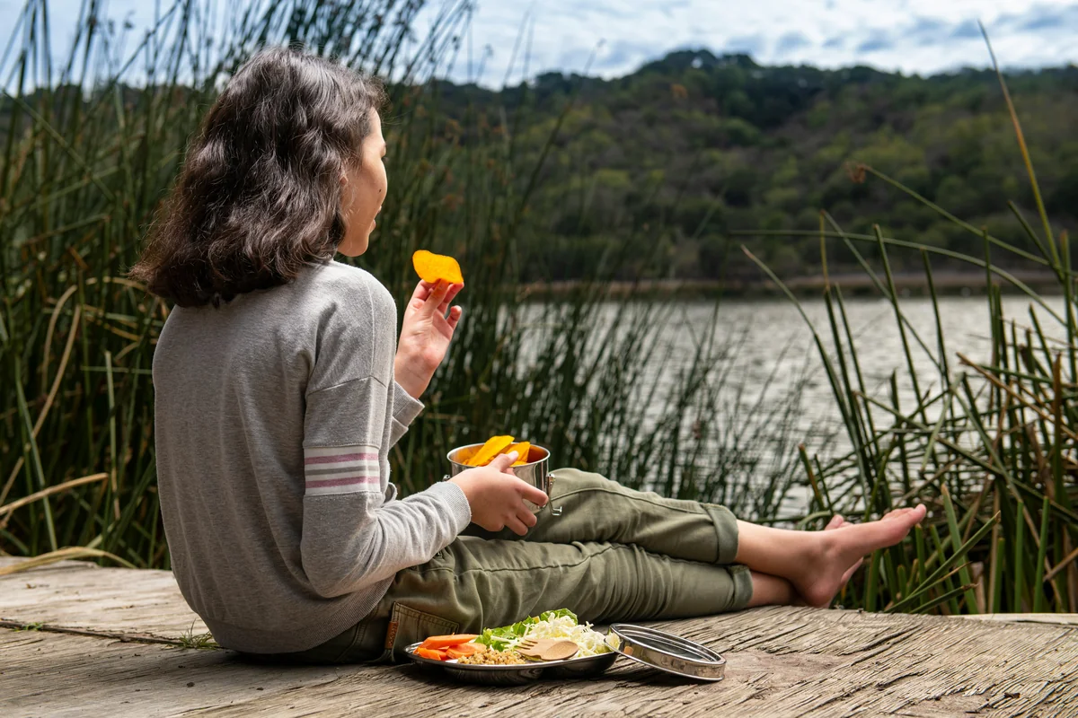 Lunchtime with stainless steel, ocean-friendly container. Eco-friendly lifestyle, outdoor living, plastic-free lifestyle, kids outside. - mindful eating