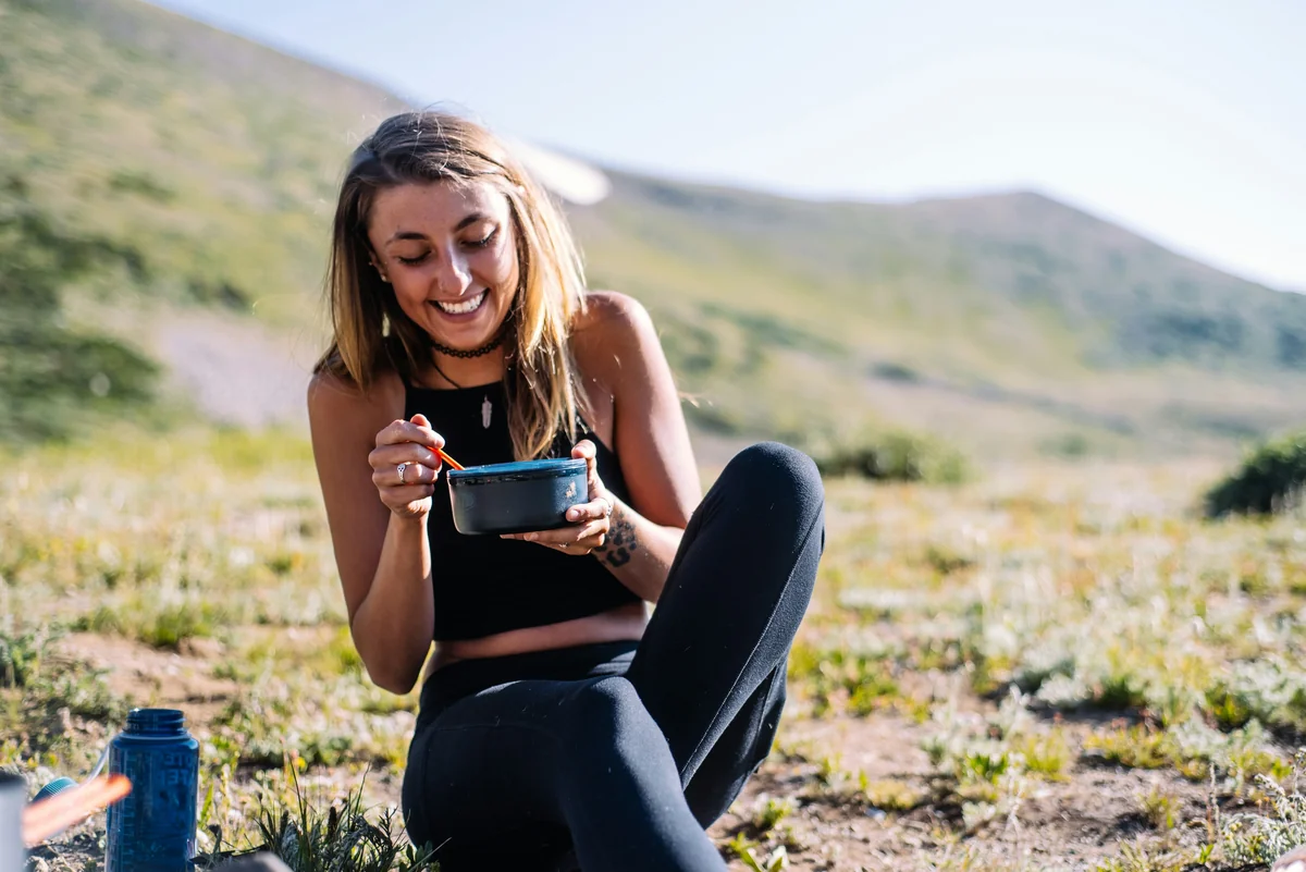 woman in black tank top and black pants sitting on ground holding blue ceramic mug during - mindful eating