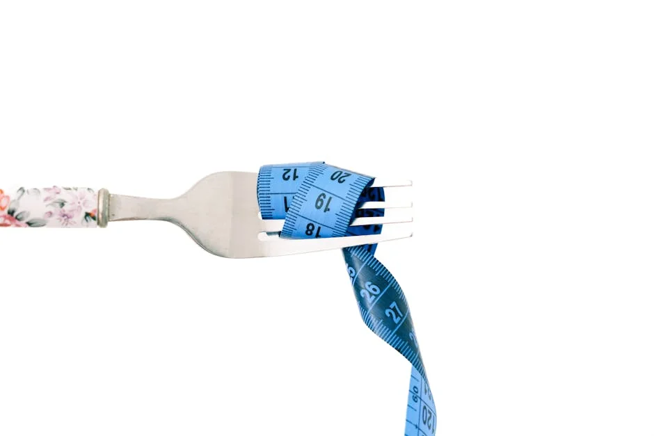 A close-up of a fork wrapped in blue measuring tape, symbolizing diet and weight management. - portion control