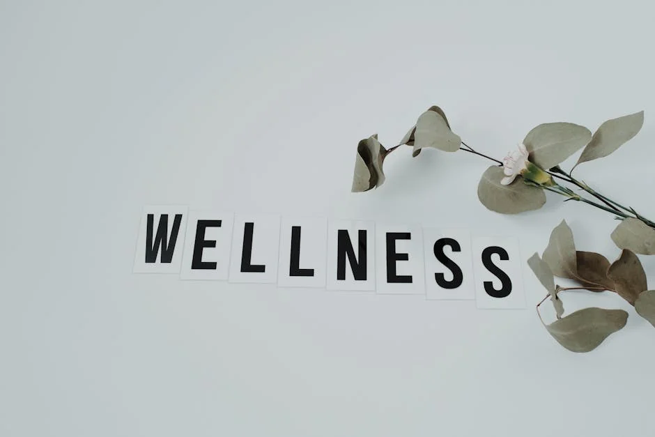 Minimalist image of the word 'wellness' with eucalyptus branch, creating a serene vibe on white background. - wellness tips