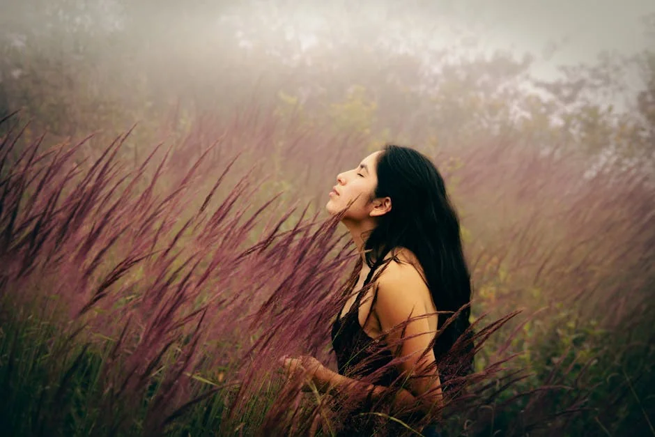 A serene young woman with eyes closed, basking in a mist-covered meadow, immersed in nature. - spiritual awakening signs